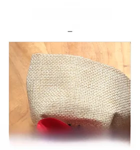 Close-up detail of rustic linen wine bottle bag with natural weave texture and red ribbon