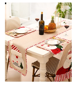 Detail of Christmas burlap table runner with embroidered Santa Claus and festive decor