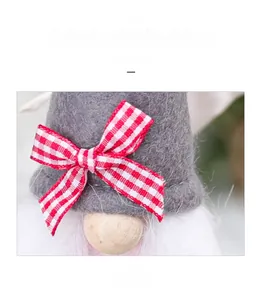 Detail of Christmas gnome plush with gray felt hat and red checkered bow decoration