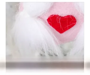 Close-up of soft plush fabric featuring a red heart embroidery on a pink dwarf gnome doll