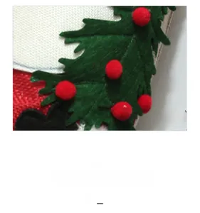 Detail of Christmas wine bottle cover with green holly leaves and red pom-poms on linen fabric
