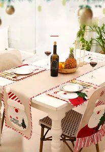 Detailed close-up of burlap Christmas table runner with Santa Claus embroidery and festive decor