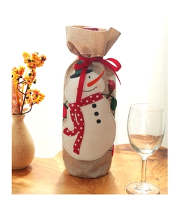 Detail view of linen Christmas wine bottle bag featuring snowman embroidery and red ribbon