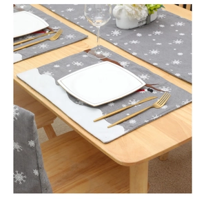 Detail eines Weihnachts-Tischläufers mit Rentier-Stickerei und weißen Schneeflocken