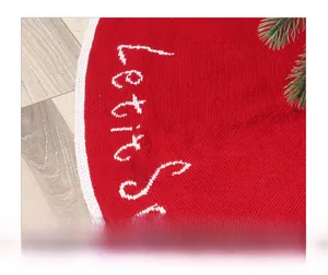 Close-up of red knitted Christmas tree skirt featuring white Let it Snow embroidery