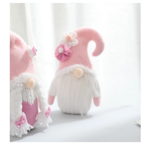 Detailed close-up of two pink and white knitted Valentine gnomes with flowers and braids