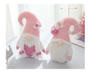 Close-up of pink and white knit gnomes with braids, hearts and flower decorated hats