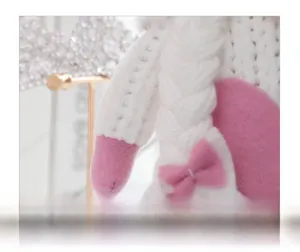 Detailed view of hand-knitted white braid on flower gnome with cute pink ribbon bow decoration