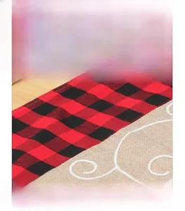 Detail of linen Christmas runner featuring red plaid fabric and fine white embroidery