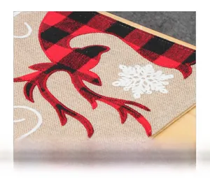 Close-up of burlap Christmas table runner featuring embroidered reindeer and snowflakes