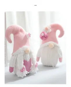 Close-up of pink and white knitted Valentine gnomes with fabric flower details and long braids