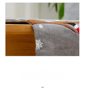 Detailed close-up of Christmas embroidery on grey linen table runner with deer patterns