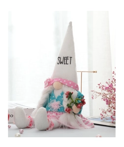 Detailed view of handmade gnome doll with white sweet hat and festive berry branch decoration