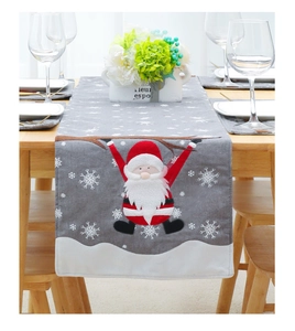 Close-up of linen Christmas table runner with Santa embroidery and white snowflake patterns