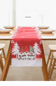 Detail of red Christmas table runner with three gnome motifs on a rustic wooden table