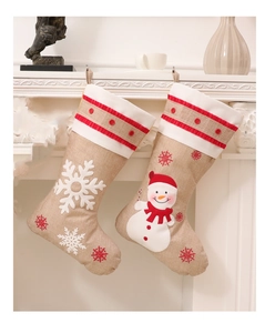 Detail of burlap Christmas stockings with snowman and snowflake embroidery on a fireplace