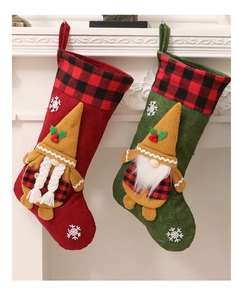 Detalle de calcetines de Navidad de gnomos rojos y verdes colgados en chimenea blanca