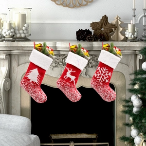 Set di 3 calze di Natale in maglia rossa con motivi a renna e albero sul caminetto