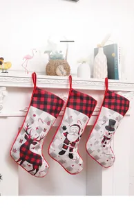 Three-piece Christmas stockings set with plaid reindeer, Santa, and snowman hanging on a fireplace