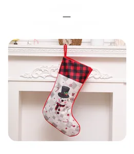 Large buffalo plaid Christmas stocking with cartoon snowman over a white fireplace