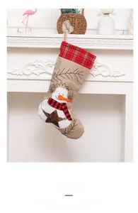 Detail of linen Christmas stocking with snowman motif and JOY embroidery on white fireplace
