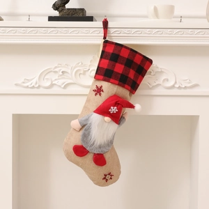 Christmas gnome stocking with red buffalo plaid cuff hanging on a white fireplace