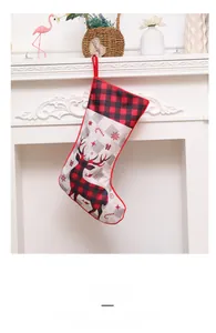 Close-up of a red and black buffalo plaid Christmas stocking with reindeer on a fireplace
