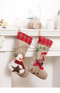 Detail of rustic linen Christmas stockings with Snowman and Star embroidery on white mantel