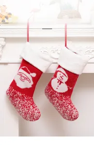 Red knitted Christmas stockings with Santa and snowman patterns hanging on a white fireplace