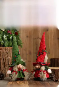 Close-up of knit Christmas gnomes with spiral hats and berry vines on wooden background