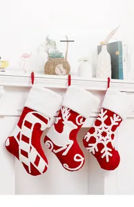 Detailed view of red Christmas stockings with reindeer and snowflake embroidery on fireplace