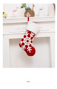 Detail of red Christmas stocking with white snowflake embroidery hanging on a white mantel