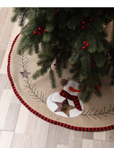 Detailed close-up of burlap Christmas tree skirt with snowman and red plaid border