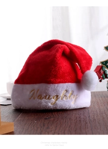 Dettaglio del ricamo dorato Naughty su un cappello di Natale in peluche rosso con ecopelliccia