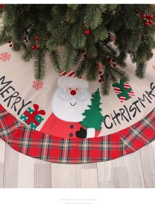 Detail of burlap Christmas tree skirt with red plaid border and Santa Claus pattern