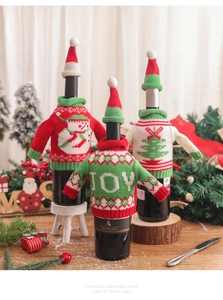 Three festive knitted Christmas wine bottle covers with mini hats and JOY sweater designs