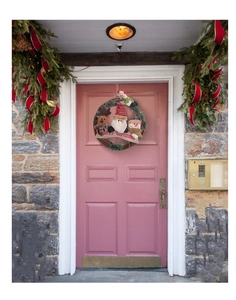 Christmas wreath with Santa, Reindeer and Snowman plush dolls on a pink wooden door