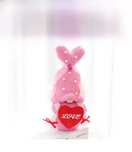 Detailed view of pink knitted Valentine gnome with LOVE sequin heart on white books