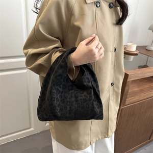 Sac à main plissé à motif léopard en velours noir porté par un mannequin en trench-coat chic