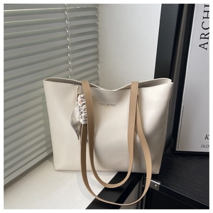 Detail of a minimalist cream tote bag with stylish silk scarf and golden brand text