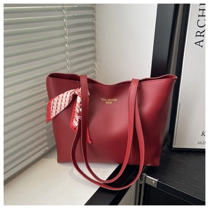 Detail of red faux leather tote bag with elegant silk scarf on long handles