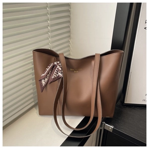 Detailed view of brown tote bag with gold logo and stylish geometric pattern silk scarf