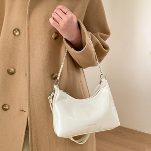 Sac hobo blanc chic avec bandoulière chaîne, porté sur un manteau en laine beige