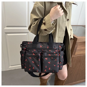 Detail of cherry print tote bag with multiple zipper pockets and adjustable shoulder strap