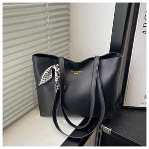 Close-up of black tote bag with gold lettering and decorative geometric print silk scarf