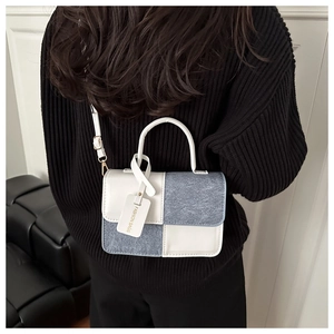 Detail of color-block crossbody bag with white leather and blue panels worn by model
