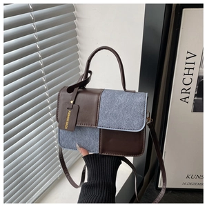 Detail of a contrast patchwork handbag with denim and brown leather on a modern background