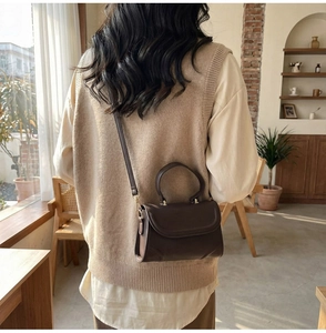 Braune Vintage-Lederhandtasche mit verstellbarem Gurt in einer gemütlichen Café-Umgebung