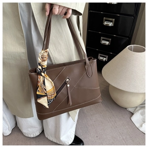 Detail of dark brown tote bag with contrast stitching and decorative silk scarf on handle