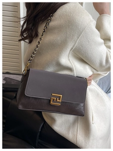 Detail of grey and coffee contrast leather bag with gold buckle and chain strap